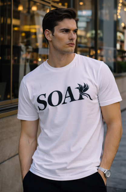 Male model wearing a white SOAR logo t-shirt standing outside a modern storefront with city reflections in the background.